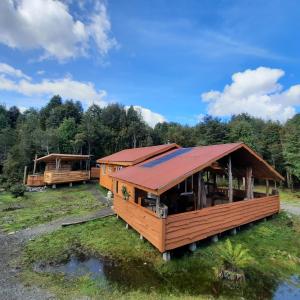 a large wooden cabin with a red roof at Pillang Likan tinas calientes, el poder del Volcan in Puerto Varas