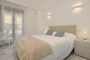 a white bedroom with a large bed and a chair at Apartamento en Moraira Moramar in Moraira