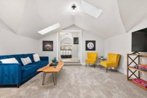 uma sala de estar com um sofá azul e cadeiras amarelas em Powell Place em Gresham