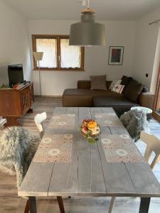 un soggiorno con tavolo in legno e divano di Appartamenti e B&B Casa Ester a Baselga di Pinè