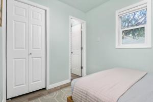 a white bedroom with a bed and a window at Coral Cottage Unit 1 in Rockaway Beach