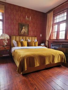 a bedroom with a large bed with a gold bedspread at Rezydencja Lawendowe Wzgórze in Zachełmie