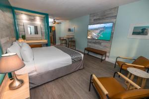 a hotel room with a bed and a flat screen tv at Suites on South Beach in Miami Beach