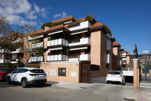 Dos coches aparcados delante de un edificio en Apartamento Las Rozas Village, en Las Rozas de Madrid