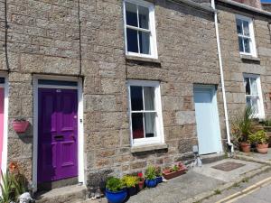 ein Backsteinhaus mit lila Türen und Topfpflanzen in der Unterkunft Traditional Fisherman's Cottage with 3 bedrooms in Mousehole