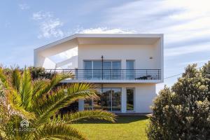 ein weißes Haus mit einem Balkon und Palmen in der Unterkunft Villa da Gama - Santa Cruz in Santa Cruz