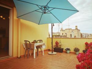 a patio with a table and a blue umbrella at Olympo in Bisceglie