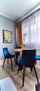 een eetkamer met een tafel en blauwe stoelen bij Apartament Italia Faktura VAT in Koszalin