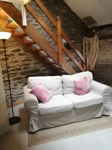 a white couch with two pink pillows in a living room at Le Courtil mezzanine in Dohan