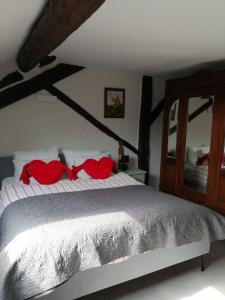 una camera da letto con un letto con cuscini rossi e uno specchio di Le Courtil mezzanine a Dohan