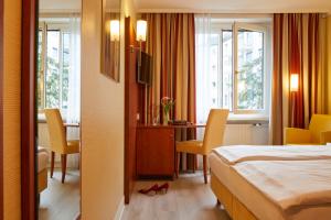 ミュンヘンにあるホテル コンコルドのベッド、テーブル、椅子が備わるホテルルームです。
