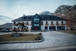 a large white building with a tree in front of it at Hotel Kulla e Bajraktarit in Bogë