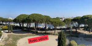 a sign in a park with trees and a harbor at Studio vue port, parking privé, terrasse, clim in Le Grau-du-Roi