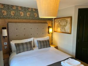 een slaapkamer met een wit bed met 2 kussens bij Queens Head Inn, Tirril in Penrith