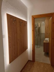 ein Badezimmer mit einer Dusche und einer Holztür in der Unterkunft CasaViva - Grazioso bilocale all’Alpe di Siusi in Kastelruth