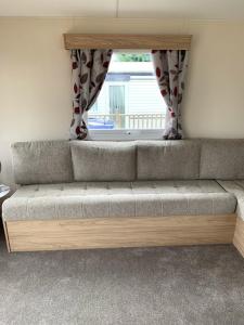 a couch in a living room with a window at Lovely 4 berth caravan on 7 Lakes Country Park at Crowle North Lincolshire in Crowle