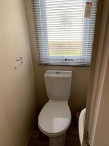 a bathroom with a white toilet and a window at Lovely 4 berth caravan on 7 Lakes Country Park at Crowle North Lincolshire in Crowle