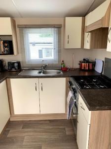 a kitchen with a sink and a stove top oven at Lovely 4 berth caravan on 7 Lakes Country Park at Crowle North Lincolshire in Crowle
