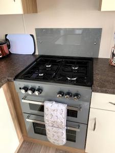 a kitchen with a stove with a towel hanging on it at Lovely 4 berth caravan on 7 Lakes Country Park at Crowle North Lincolshire in Crowle