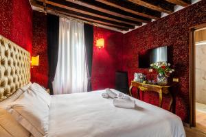 a bedroom with red walls and a bed with two towels at Ca' Maria Callas in Venice +28 photos