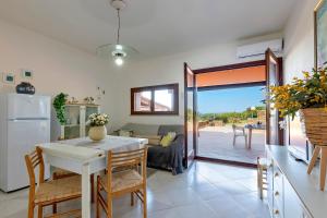 スティンティーノにあるSARDINIA RE - Villino Punta Negraのテーブルと椅子のあるキッチンとリビングルーム