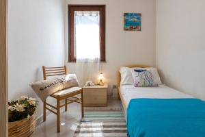 una camera con un letto e una sedia e una finestra di SARDINIA RE - Villino Punta Negra a Stintino