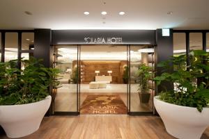 Solaria Nishitetsu Hotel Fukuoka في فوكوكا: لوبي فيه نباتات الفخار امام الفندق