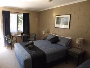 Sunbird Motel في تاونزفيل: غرفة نوم بسرير وطاولة وكراسي