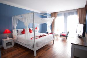 a bedroom with a white bed with a canopy at The Frangipani Royal Palace Hotel in Phnom Penh