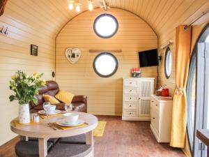 ein Wohnzimmer mit einem Tisch in einem winzigen Haus in der Unterkunft Wrekin Lodge in Much Wenlock