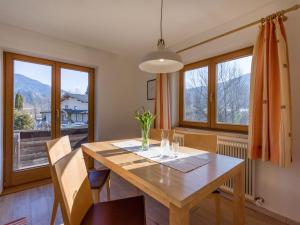 een eetkamer met een houten tafel en ramen bij Apartment Rabl in Kirchbichl