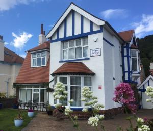 a white and blue house with flowers in the yard at Between the Bays exclusively for Adults in Llandudno