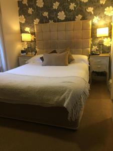 una camera da letto con un grande letto bianco con due comodini di Castle Lodge Wilton a Ross on Wye