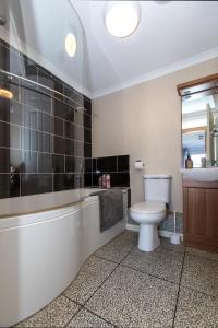 a bathroom with a toilet and a tub and a sink at Carnoustie Dreams in Wisbech