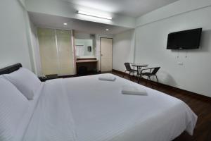 Un dormitorio con una cama blanca grande y una mesa en The Bless Residence, en Hat Yai