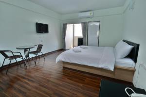 Un dormitorio con una cama y una mesa y sillas. en The Bless Residence, en Hat Yai