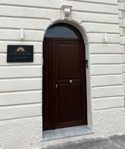 eine braune Tür in einem weißen Gebäude mit einem Schild in der Unterkunft Le Vie Del Centro Luxury Room in Matera