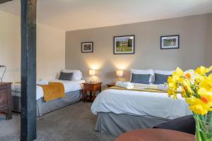 Charney Manor في Kingston Bagpuze: سريرين في غرفة بها ورود صفراء في الغرفة