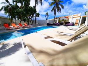 a swimming pool with white lounge chairs and a swimming pool at Bubali Residence in Palm-Eagle Beach