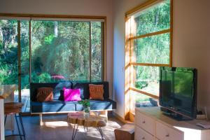 sala de estar con sofá y ventana grande en Cabaña a pasos del río rodeada de un hermoso entorno nativo natural, en Villarrica