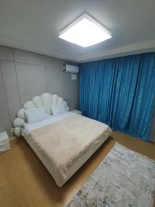 a bedroom with a large bed with a blue curtain at апартаменты в ЖК Хайвил in Astana