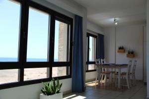 a dining room with large windows and a table at Apartamento (Cotillo Mar) con vistas al Mar in El Cotillo