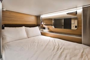 a bedroom with a white bed and a mirror at Pod Hotel in Montréal