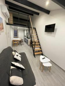 a living room with a couch and a staircase at Villa Rubia Studio mezzanine au cœur des Corbières in Fabrezan