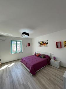 Un dormitorio con una cama morada en una habitación blanca en Casa Vacanze Sa Piazza, en Dorgali