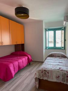 1 dormitorio con 2 camas y manta rosa en Casa Vacanze Sa Piazza, en Dorgali