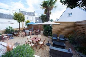 un patio avec des chaises, des tables et des parasols dans l'établissement Hotel les Alignements, à Carnac