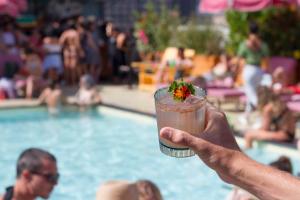 a hand holding a drink in front of a swimming pool at Freehand Los Angeles in Los Angeles