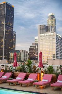 a row of pink lounge chairs and a pool on a rooftop at Freehand Los Angeles in Los Angeles