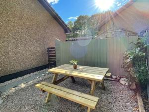 drewniany stół piknikowy z doniczką siedzącą obok płotu w obiekcie The Wee Hoose near Loch Ness, private garden, private parking w mieście Drumnadrochit
